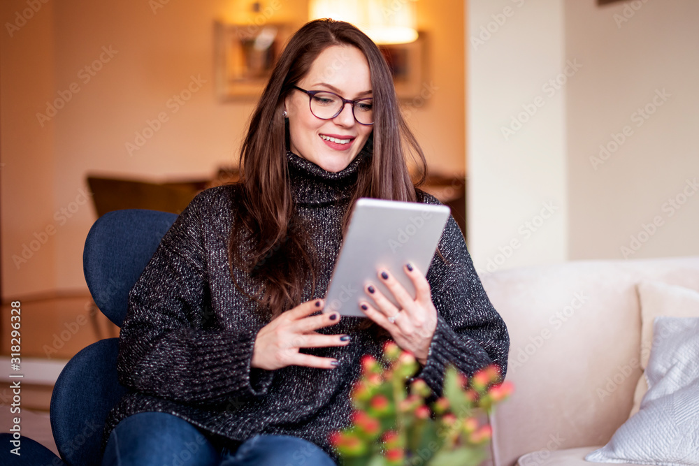 Young woman using digital tablet while relaxing in the armchair at home Young woman using digital tablet while relaxing in the armchair at home