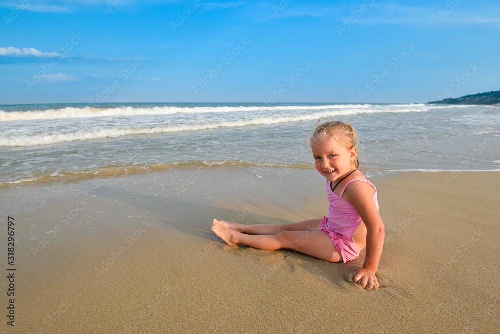Girl in pink swimsuit sitting on the beach and looking at the morning sea. Girl in pink swimsuit sitting on the beach and looking at the morning sea.