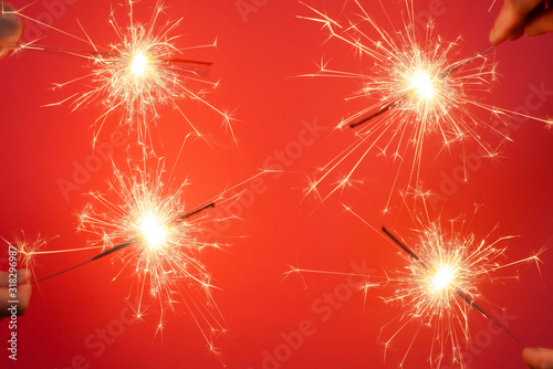 Christmas or Happy New Year party banner concept. Close up of Bright burning four sparklers on a red