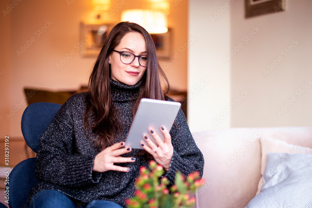 Young woman using digital tablet while relaxing in the armchair at home Young woman using digital tablet while relaxing in the armchair at home