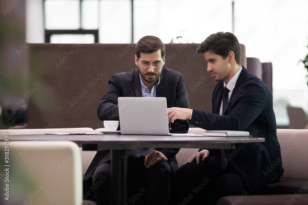 Focused employees in suits discussing corporate software. Focused employees in suits discussing corporate software.