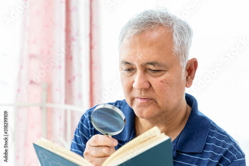 Foto Happy elderly senior man male enjoy reading book using magnifying glass