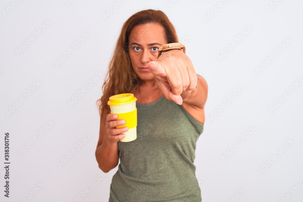 Middle age mature woman drinking a take away cup of coffee over isolated background pointing with finger to the camera and to you, hand sign, positive and confident gesture from the front Middle age mature woman drinking a take away cup of coffee over isolated background pointing with finger to the camera and to you, hand sign, positive and confident gesture from the front