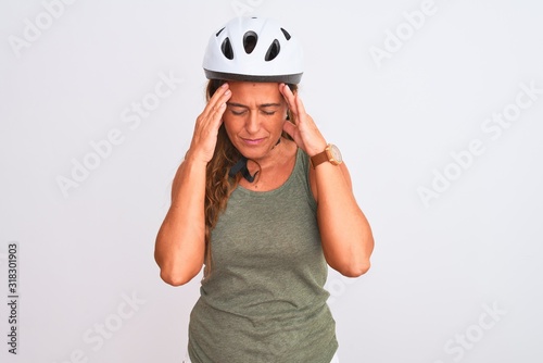 Middle age mature cyclist woman wearing safety helmet over isolated background with hand on headache because stress. Suffering migraine.