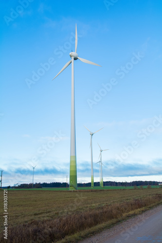 Wind electricity generator park  visible green farming fields  trees  grass and blue skies with clouds