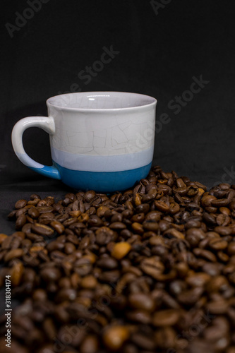 Coffee cup with grains against dark background. Close-up with copy space for your text.