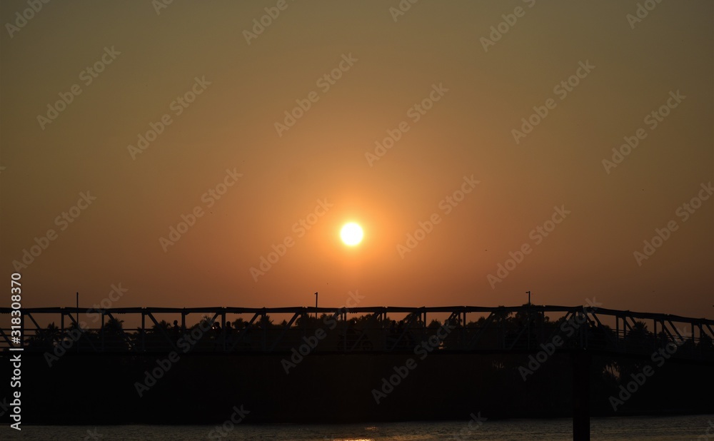 Silhouette of a bridge at dusk with beautiful sunset and red spread sky background
