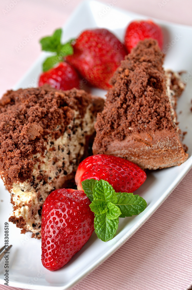 Homemade mole hole cake with whipped cream, banana, strawberries and fresh mint leaves on white decorative shaped plate. Pink place setting. Close-up.