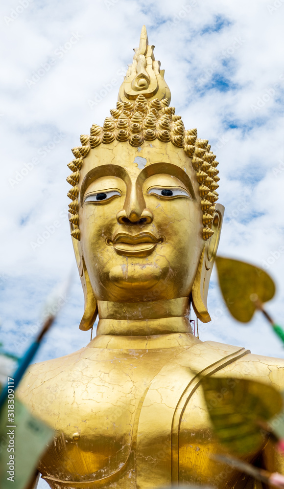 Big Buddha sculpture in temple with blue sky and clouds