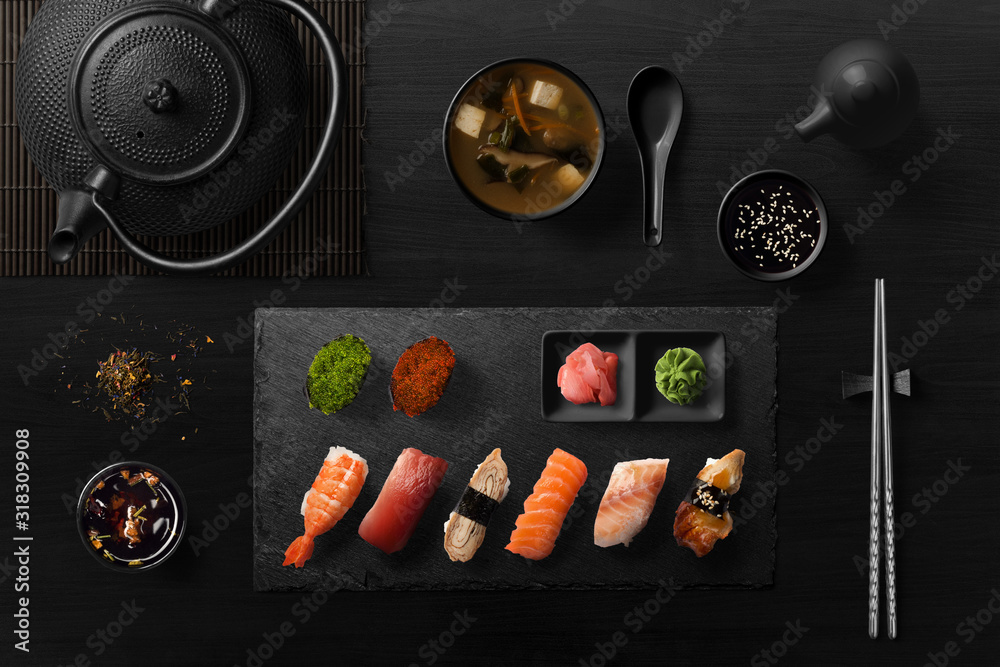 Sushi rolls, sashimi set, miso soup and teapot, on dark wooden table, Japanese food, top view. - obrazy, fototapety, plakaty 