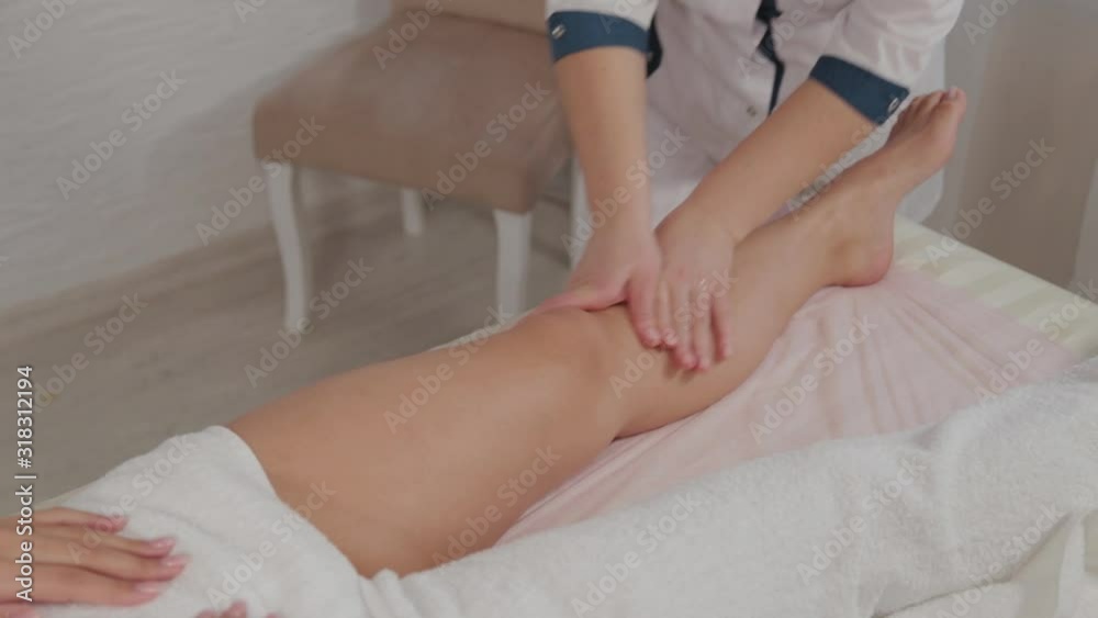 Female massage therapist doing massage over the entire length of the legs of a young girl. Female massage therapist doing massage over the entire length of the legs of a young girl.