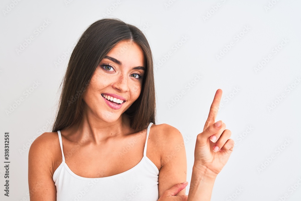 Young beautiful woman wearing casual t-shirt standing over isolated white background very happy pointing with hand and finger to the side Young beautiful woman wearing casual t-shirt standing over isolated white background very happy pointing with hand and finger to the side