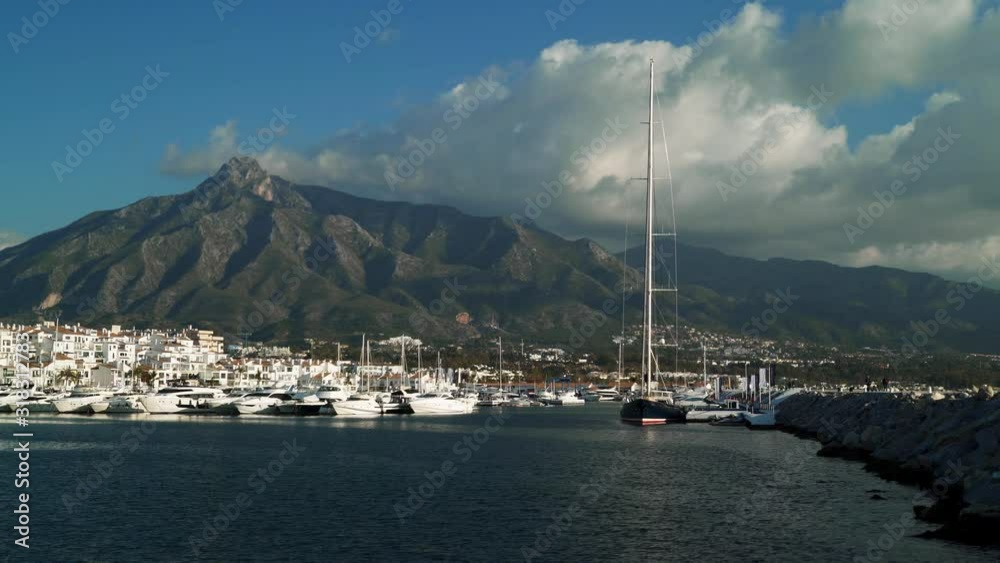 Gimbal pan shot left to right of luxury yacht club row at Marbella and the pier at daylight. Yachts in the marina of Luxury yacht of Puerto Banus located near Marbella, Spain Gimbal pan shot left to right of luxury yacht club row at Marbella and the pier at daylight. Yachts in the marina of Luxury yacht of Puerto Banus located near Marbella, Spain