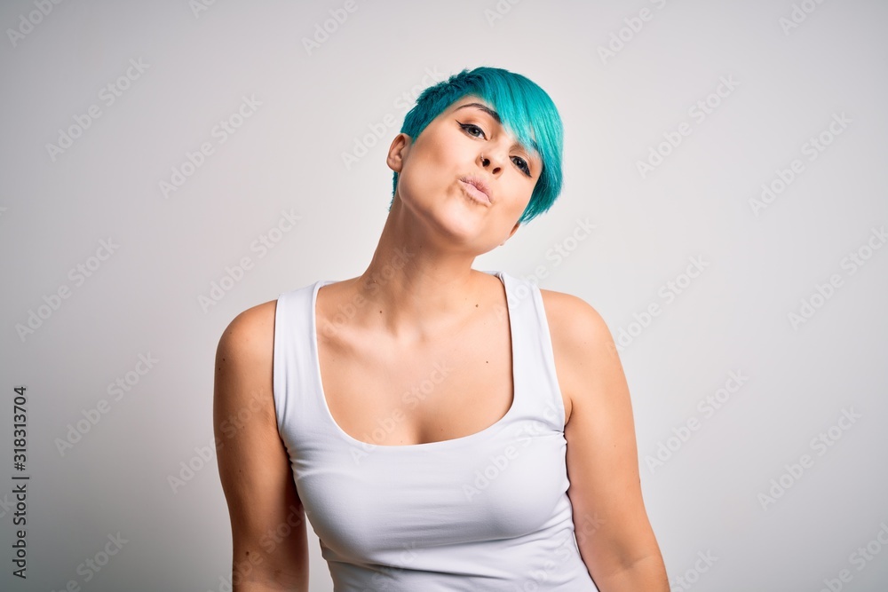 Young beautiful woman with blue fashion hair wearing casual t-shirt over white background looking at the camera blowing a kiss on air being lovely and sexy. Love expression. Young beautiful woman with blue fashion hair wearing casual t-shirt over white background looking at the camera blowing a kiss on air being lovely and sexy. Love expression.