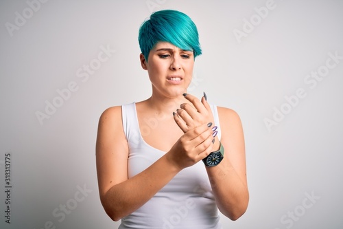 Young beautiful woman with blue fashion hair wearing casual t-shirt over white background Suffering pain on hands and fingers, arthritis inflammation © Krakenimages.com