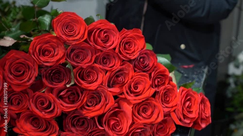 the flower seller is making a bouquet of red roses