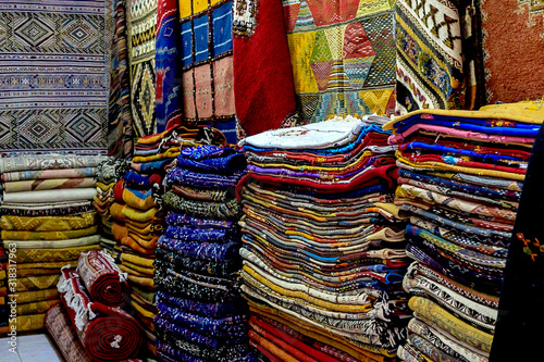 Moroccan carpets with vibrant colors for sale in the narrow street of Rabat in Morocco with selective focus. © Natallia