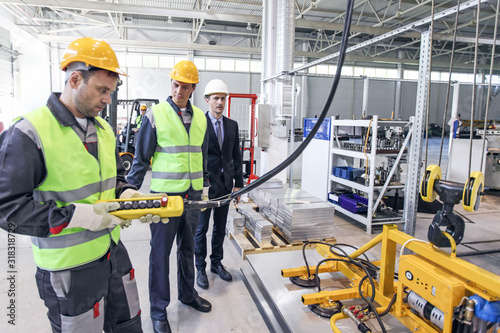 Workers and electro magnets lifting steel plate