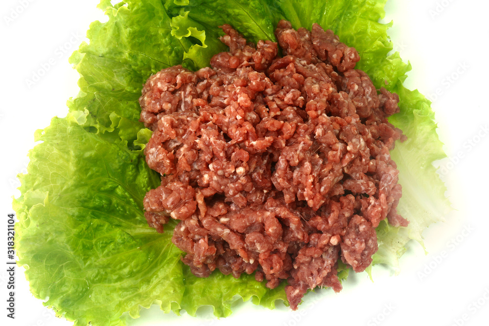 raw minced meat isolated on white background with green leaves and condiments.
