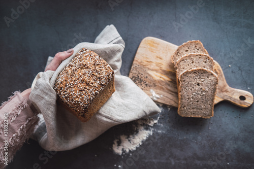 Woman's hands holding a loaf of buckwheat bread with chia.