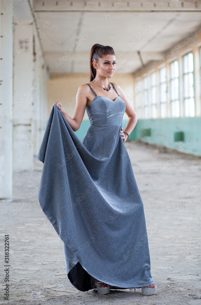 Beautiful teen girl playing with her long, glamorous silver dress. Beautiful teen girl playing with her long, glamorous silver dress.