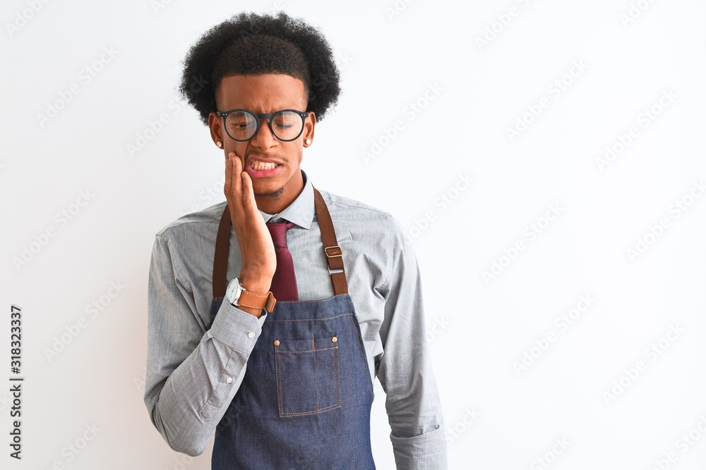 Young african american shopkeeper man wearing apron glasses over isolated white background touching mouth with hand with painful expression because of toothache or dental illness on teeth. Dentist Young african american shopkeeper man wearing apron glasses over isolated white background touching mouth with hand with painful expression because of toothache or dental illness on teeth. Dentist