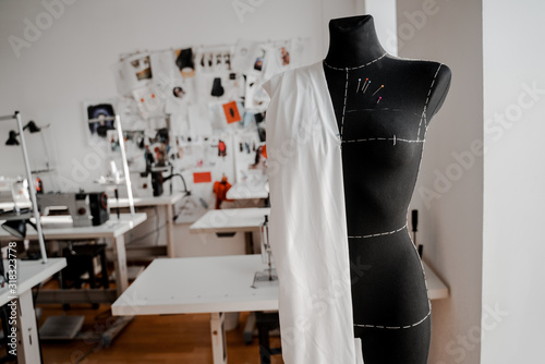 Mannequin with fabric on the shoulder and stuck pins into the fabric in design studio for sewing and tailoring, special education concept photo