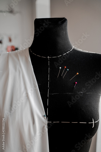 Mannequin with fabric on the shoulder and stuck pins into the fabric in design studio for sewing and tailoring, special education photo