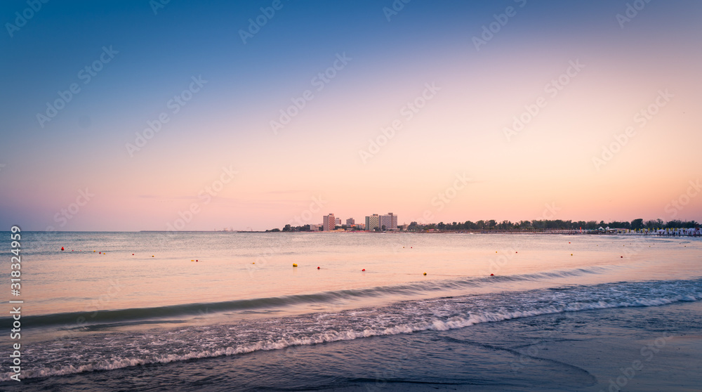 The sea with hotels in the background at sunset
