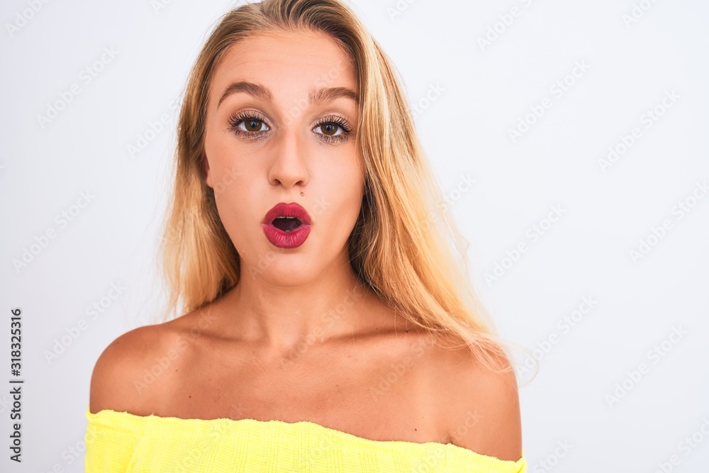 Naklejka premium Young beautiful woman wearing yellow t-shirt standing over isolated white background scared in shock with a surprise face, afraid and excited with fear expression