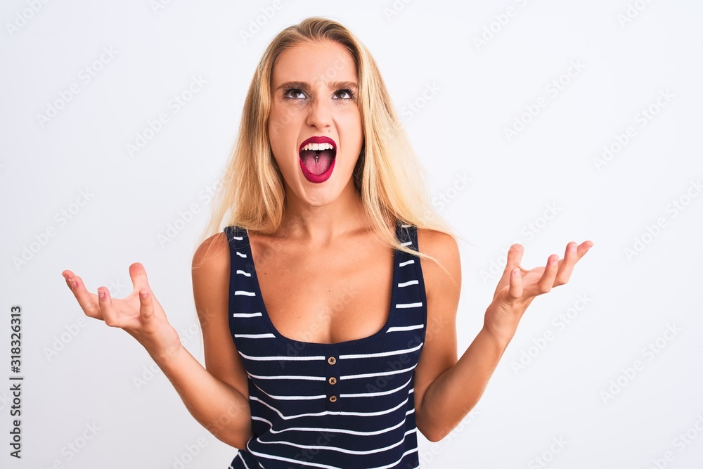 Young beautiful woman wearing casual striped t-shirt standing over isolated white background crazy and mad shouting and yelling with aggressive expression and arms raised. Frustration concept. Young beautiful woman wearing casual striped t-shirt standing over isolated white background crazy and mad shouting and yelling with aggressive expression and arms raised. Frustration concept.