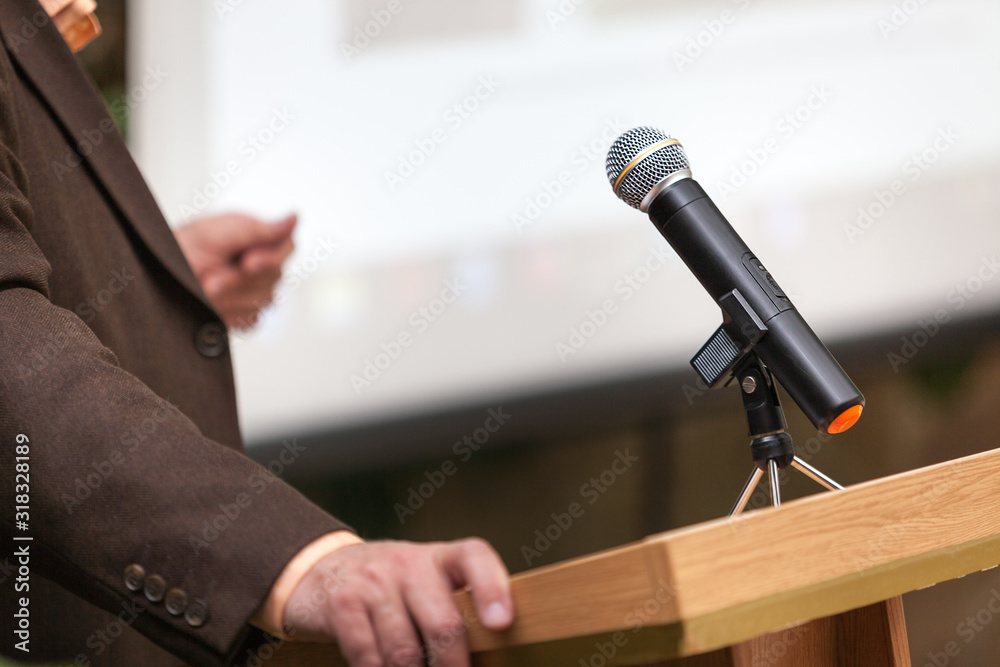 A man stands a with a microphone and holds a conference