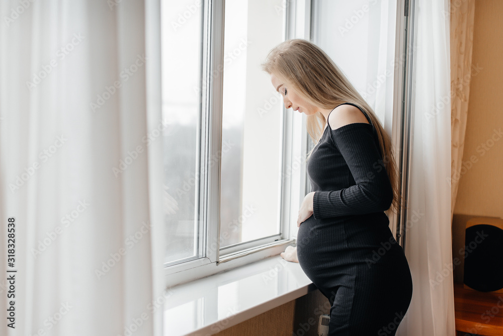 A pregnant girl is breathing fresh air from the window A pregnant girl is breathing fresh air from the window