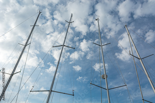 Conceptual view of frout sail boat masts under cloudy sky.