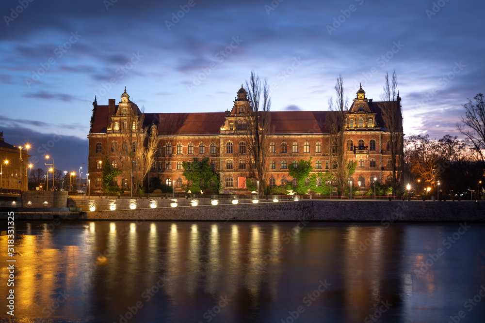 Wroclaw, Poland. Illuminated historic building of National Museum reflecting in Oder river at dusk
