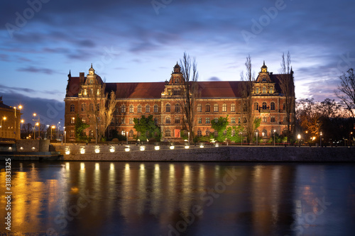 Wroclaw, Poland. Illuminated historic building of National Museum reflecting in Oder river at dusk
