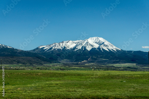 green pasture with snow cap mountain range in background 