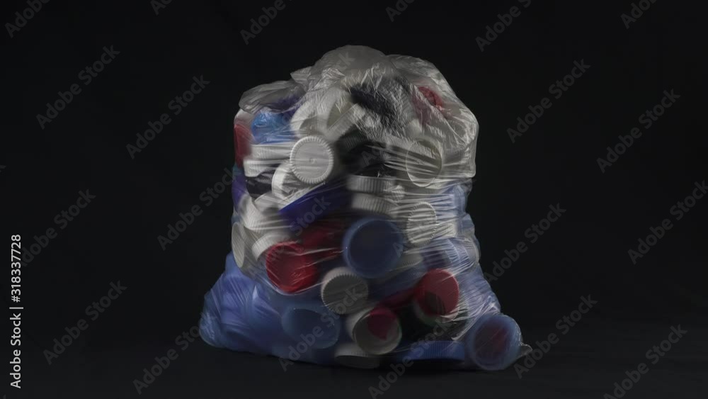 Big transparent bag filled with plastic bottle caps for recycling. A