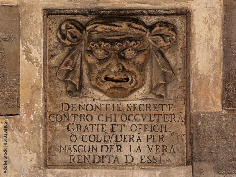 old stone relief of a mans face with open mouth