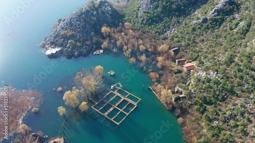 Karuc on Lake Skadar in Montenegro, Europe is an old fishing village. Aerial circling around shot on a sunny day. Bands of various shades of green in water due to differences in depth and temperature. photo