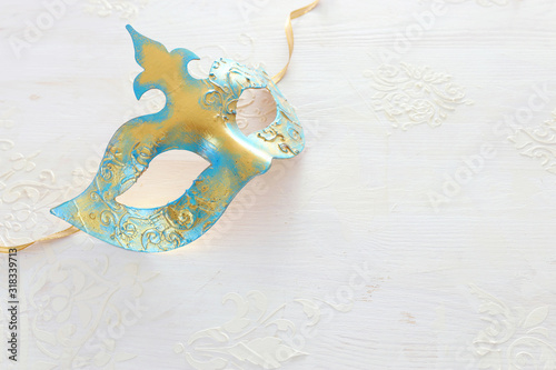 Photo of elegant and delicate gold Venetian mask over white wooden background