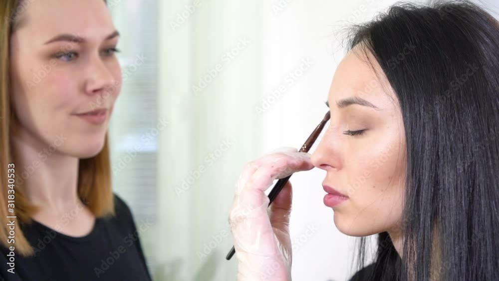 Makeup artist doing the make up for beautiful brunette woman Makeup artist doing the make up for beautiful brunette woman