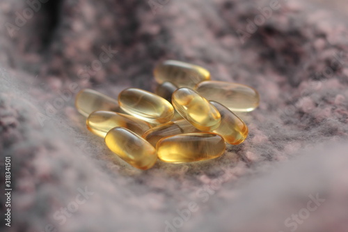 Closeup of fish oil capsules on knitted fabric. Supplement for autumn and winter.
