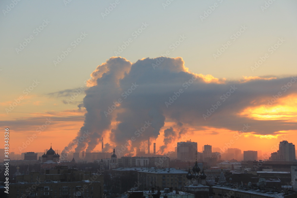 Sunset over the city with steam from TPP pipes
