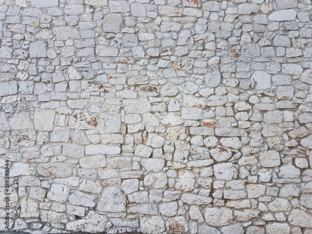 Fototapeta premium Ancient medieval stone masonry. Texture of a fragment of a wall of an old structure. A background for design and creative work. Decoration and exterior decoration of the building. Construction works