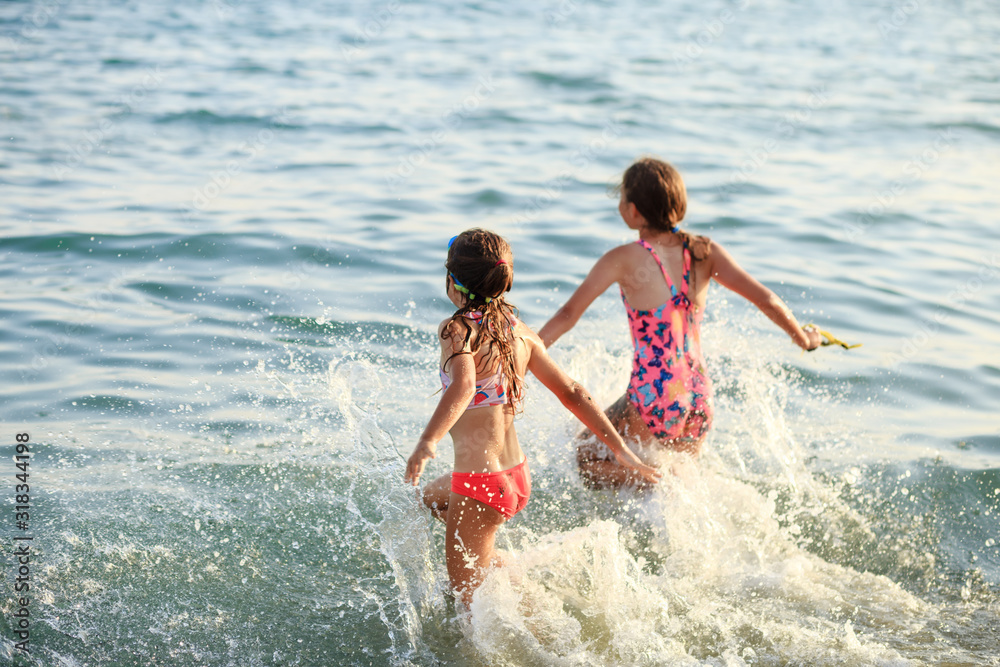 Two Cute Little Girls playing with waves by the Sea at sunset. Summer Sunny Day, Ocean Coast, happy Kids concept, soft focused Two Cute Little Girls playing with waves by the Sea at sunset. Summer Sunny Day, Ocean Coast, happy Kids concept, soft focused