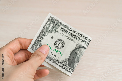 Hand with a one-dollar bill on a wooden background, an image of money