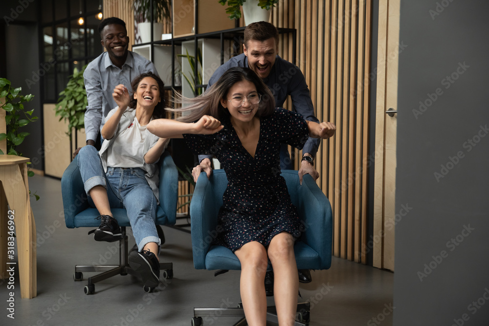 Overjoyed multiethnic colleagues have fun racing in office Overjoyed multiethnic colleagues have fun racing in office