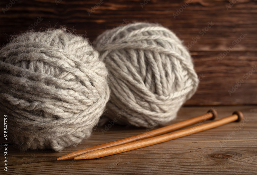 Balls of yarn and knitting needles on a wooden background.
