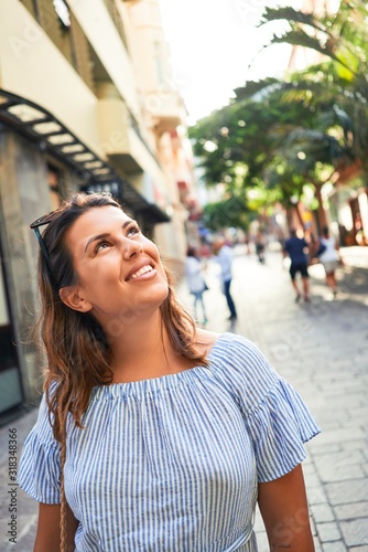 Young beautiful woman smiling happy walking on city streets on a sunny day of summer